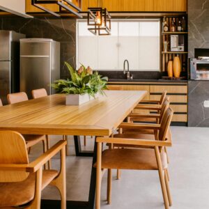Stylish modern kitchen featuring wooden dining table with chairs, stainless steel fridge, and indoor plants.