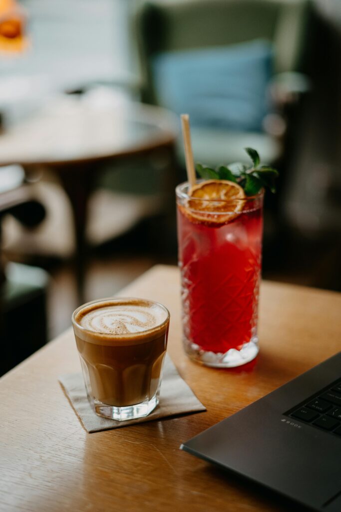 pexels-photo-15415487-15415487 Image of a cozy café setting featuring a latte and a fruit cocktail on a wooden table.