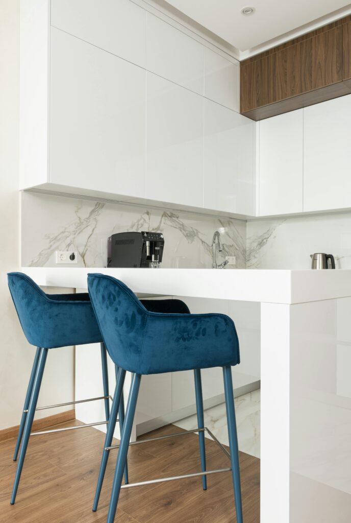 pexels-photo-6636287-6636287 Stylish modern kitchen with white cabinets and blue velvet bar stools for a contemporary look.