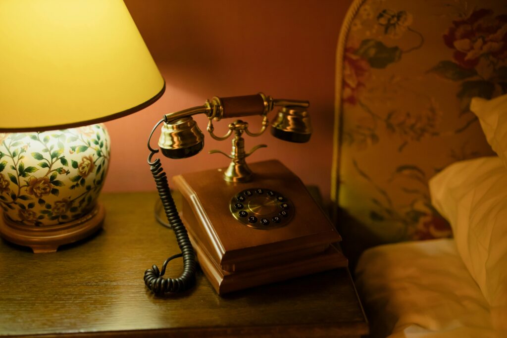 pexels-photo-7609119-7609119 Classic hotel room decor featuring an antique telephone and floral lamp.