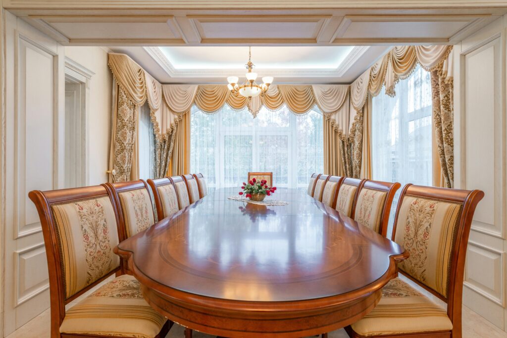 pexels-photo-8092433-8092433 A beautifully decorated dining room featuring a long wooden table and ornate curtains, exuding elegance and luxury.